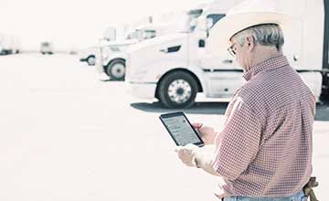 man holding tablet in front of fleet of trucks